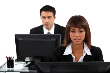 Two office workers sat at their desks clipart