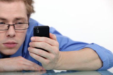 Tired man looking at his cellphone clipart