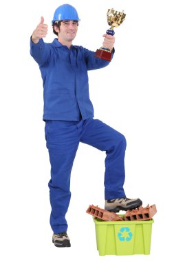 Builder stood with trophy and box of recyclable materials clipart