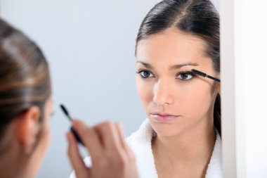 Brunette applying eye make-up clipart