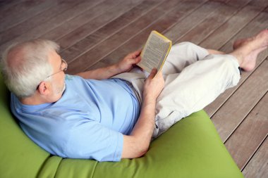 Man on couch reading book clipart