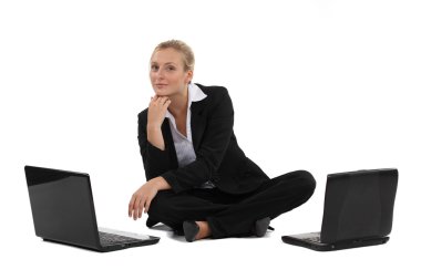 Blond businesswoman sat on the floor with two laptops clipart