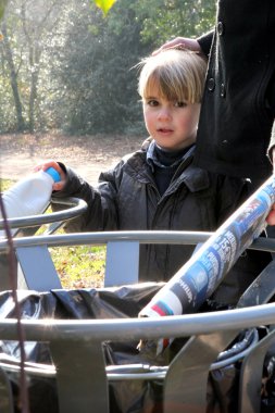 Little boy using a trash can in the park clipart