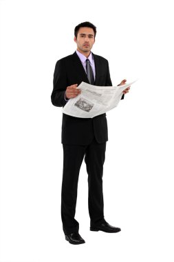 Businessman reading a newspaper clipart