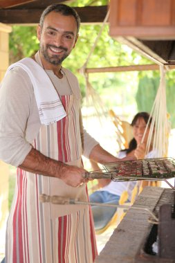 Man preparing kebabs on bbq clipart