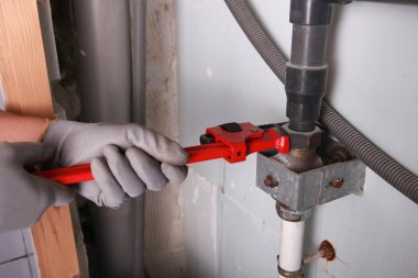 Plumber turning bolt with wrench clipart