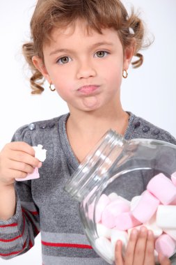 Little girl eating marshmallows from a jar clipart