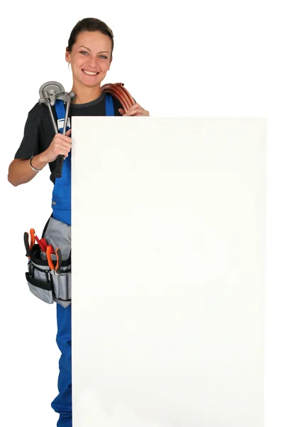 Encanador fêmea com ferramentas do comércio e uma grande placa deixou em branco para sua mensagem — Fotografia de Stock