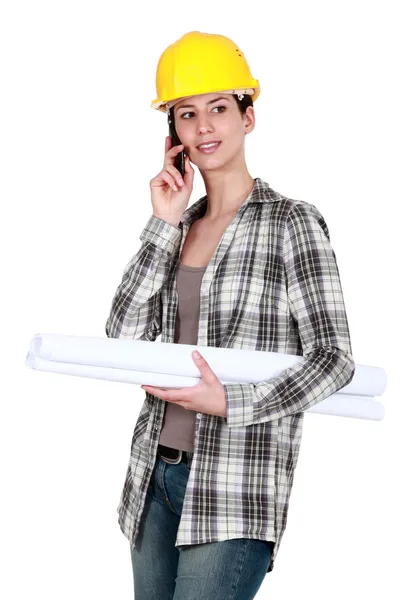 Женщина в каске с планами и сотовым телефоном — стоковое фото