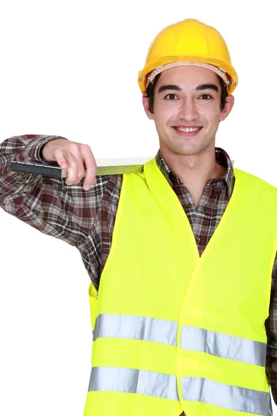 Construction worker carrying a heavy plank — Stock Photo, Image
