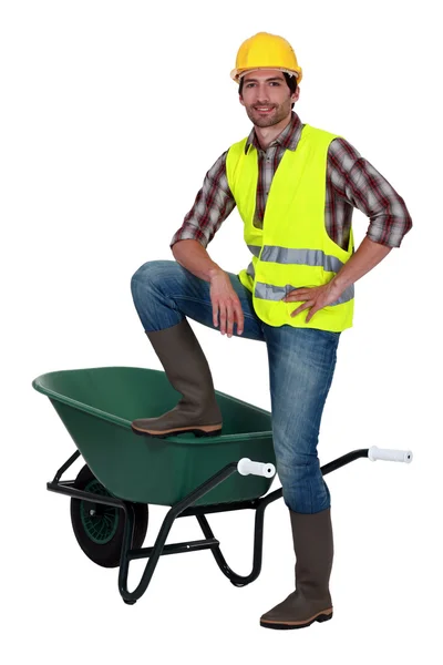 Man casually stood by empty wheelbarrow — Stock Photo, Image