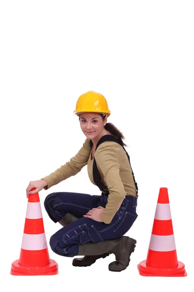 Feminino trabalhador rodoviário ajoelhado por cones — Fotografia de Stock