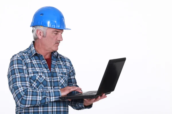Senior hantverkare innehar en laptop — Stockfoto