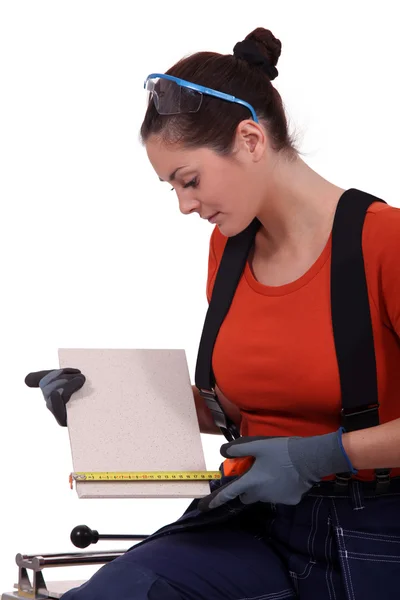 Tradeswoman measuring a tile — Stock Photo, Image