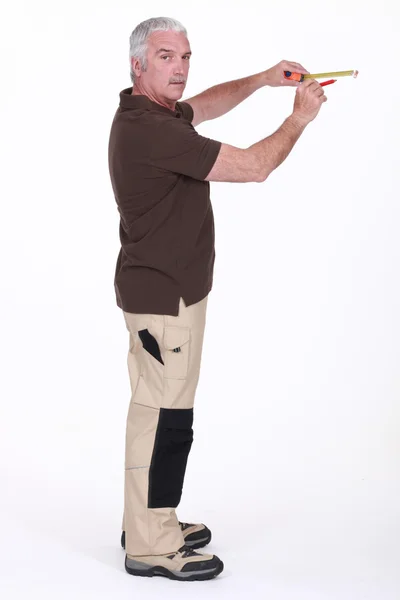 Šedovlasý muž měřící stěny — Stock fotografie