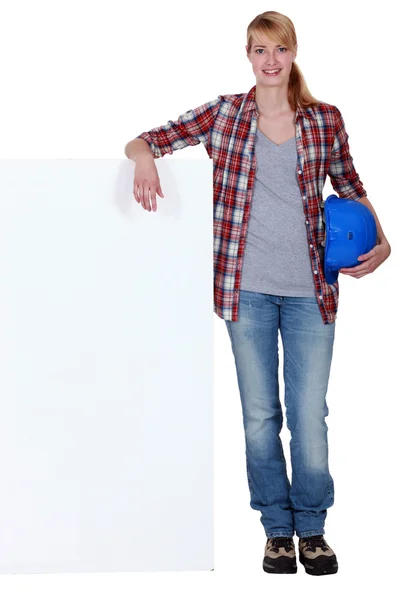 Construtora feminina inclinada contra cartaz em branco — Fotografia de Stock