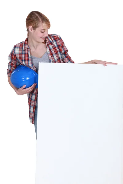 Tradeswoman looking at a blank sign with interest — Stock Photo, Image