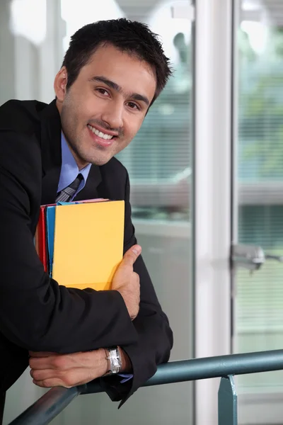 Un hombre de negocios sonriente sosteniendo archivos —  Fotos de Stock