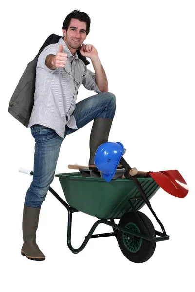 Um construtor posando perto de um carrinho de mão — Fotografia de Stock
