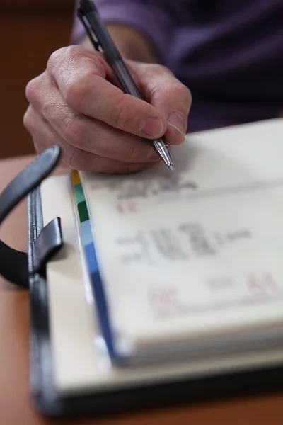 Fechar-se de uma mão masculina escrevendo em um organizador pessoal — Fotografia de Stock