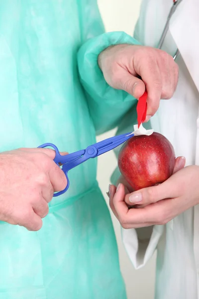 Surgeon healing apple with plastic instruments — Stock Photo, Image