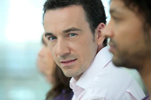 Headshot en stilig man som står med kollegor i en rad — Stockfoto