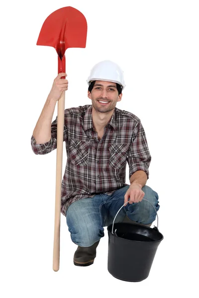 Řemeslník drží lopatu a kbelík — Stock fotografie