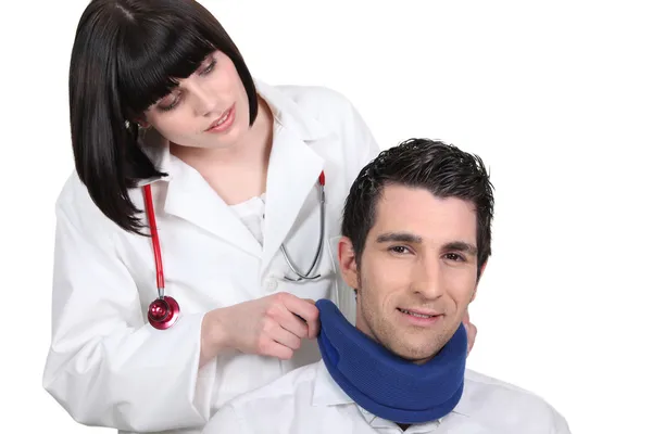 Женщина-врач накладывает шейный корсет на пациента мужского пола — стоковое фото