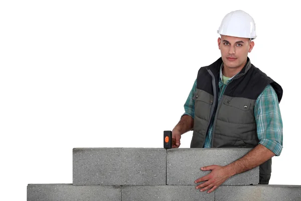 Pedreiro posando por parede de concreto isolado no branco — Fotografia de Stock