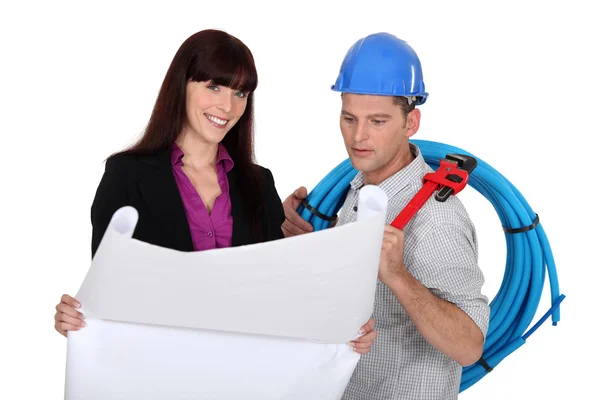 Geschäftsfrau und Handwerker schauen sich einen Entwurf an — Stockfoto