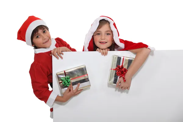 Crianças vestidas com traje de Natal com presentes — Fotografia de Stock