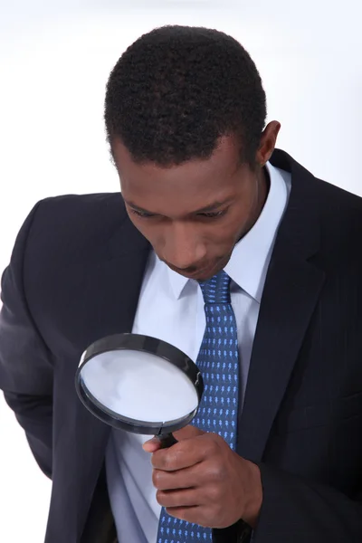 Nieuwsgierig man inspectie van een object met een vergrootglas — Stockfoto
