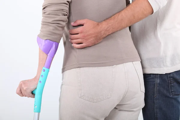 Closeup back view of man supporting woman on crutches — Stock Photo, Image