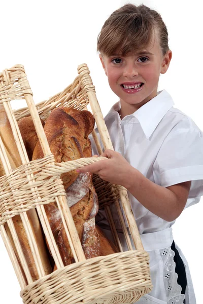 Malá dívka oblečená jako pekař nesoucí chléb v košíku — Stock fotografie