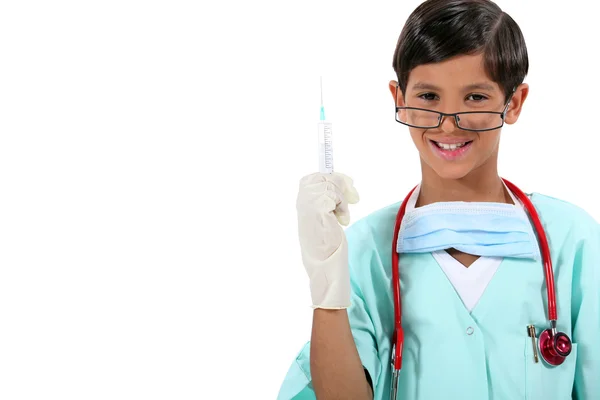 Мальчик, одетый как доктор, держит иглу — стоковое фото
