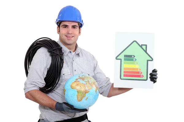 Eletricista segurando um globo e um sinal de classificação de eficiência energética — Fotografia de Stock