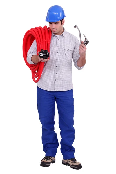 Водопроводчик держит копилку и кран — стоковое фото