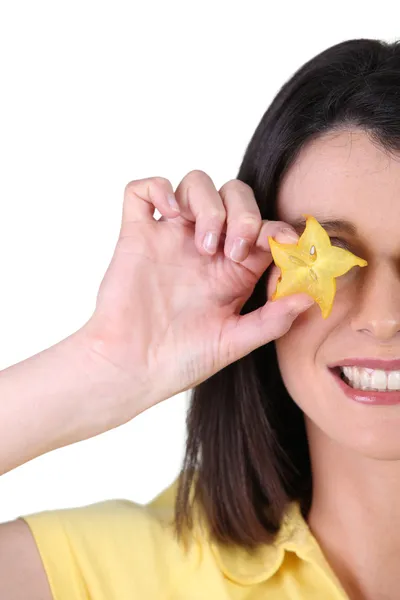 Жінка прикриває око шматочком зіркових фруктів — стокове фото