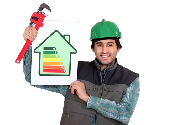 Comerciante sosteniendo una llave de tubo y un signo de calificación de eficiencia energética — Foto de Stock