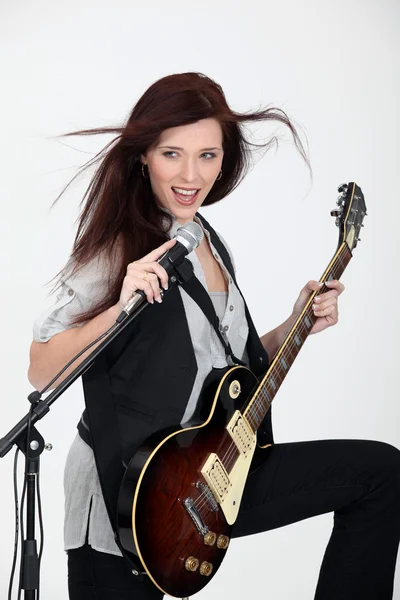 Mujer joven tocando la guitarra y cantando — Foto de Stock