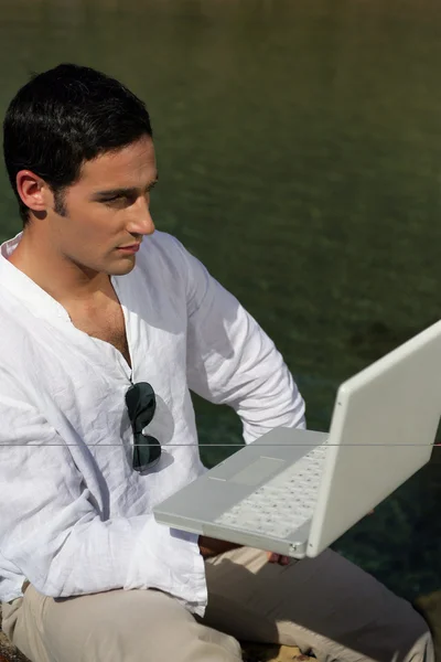 Człowiek za pomocą laptopa przez stronę jeziora — Zdjęcie stockowe