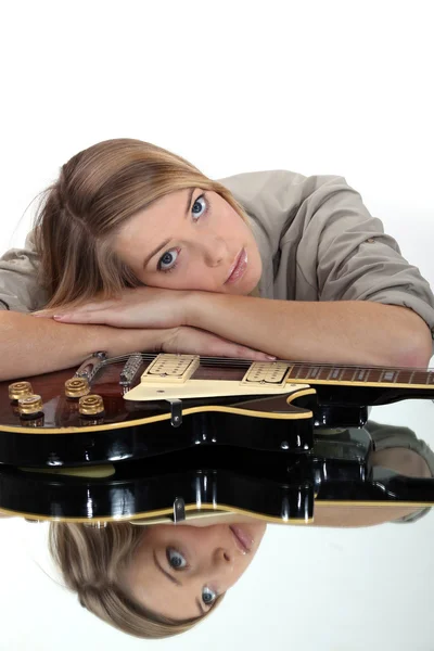 Eine süße Blondine, die sich auf einer Gitarre ausruht. — Stockfoto