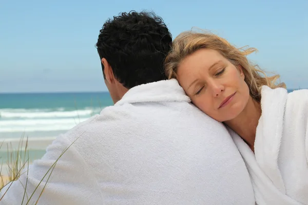Man en vrouw op het strand in badjassen — Stockfoto
