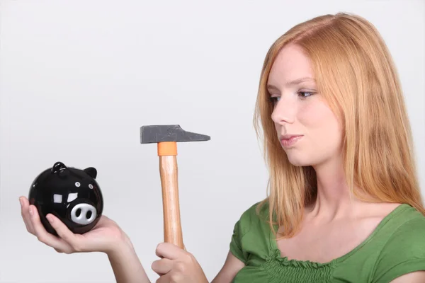 Young woman holding piggy bank and hammer — Stock Photo, Image