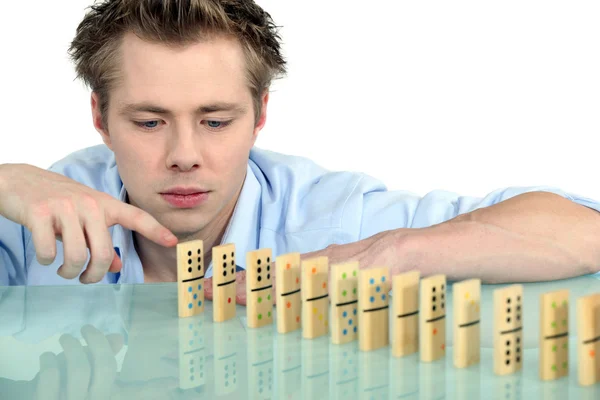Young man with a row of dominoes — Stock Photo, Image