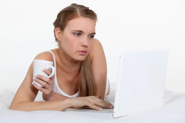 Fiatal nő szóló ágyban laptop és kávé — Stock Fotó