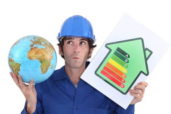 Craftsman holding an energy consumption label and a globe — Stock Photo, Image
