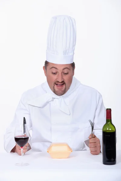 Шеф-повар ест фаст-фуд и пьет вино — стоковое фото