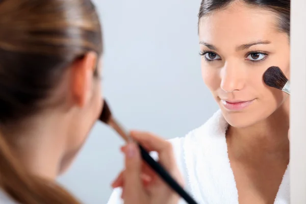 Mulher aplicando blusher em um espelho — Fotografia de Stock