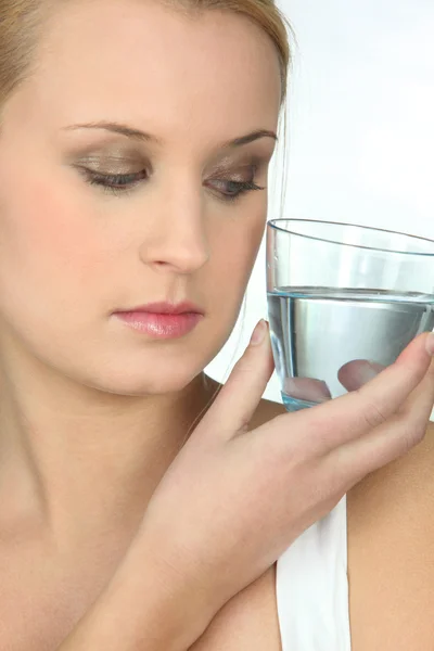 Mulher olhando para um copo de água — Fotografia de Stock